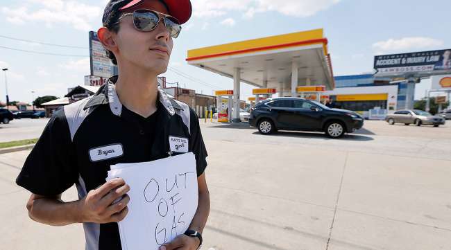 Gas station employee holds "out of gas" sign