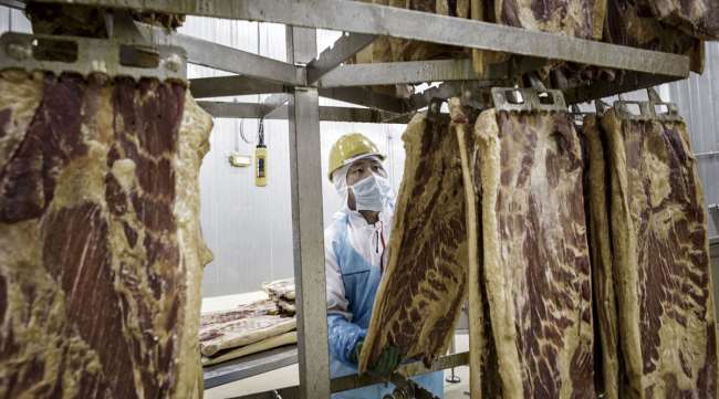 An employee handles a Smithfield Foods pork belly on a production line in China.