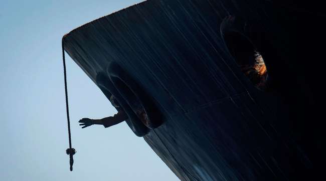 A crew member reaches for a rope at the Grace 1 supertanker.