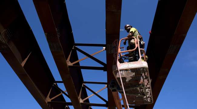 A contractor stands on a cherry picker to work on steel beams during highway construction between U.S. Route 23 and U.S. Route 52 near Portsmouth, Ohio.