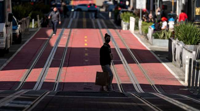 A pedestrian wearing a protective mask carries a shopping bag in San Francisco. (David Paul Morris/Bloomberg News)