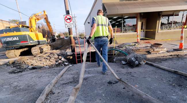 Workers fix a sewer main below the sidewalk in New Orleans