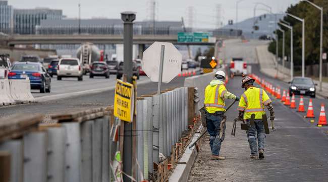 Contractors work on a road under repair along Highway 101 in San Mateo, Calif.