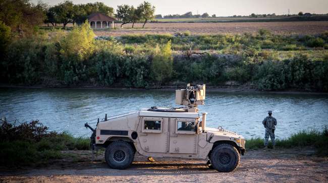 A soldier from the 36th Infantry Division, Texas Army National Guard observes a section of the Rio Grande River at sunset