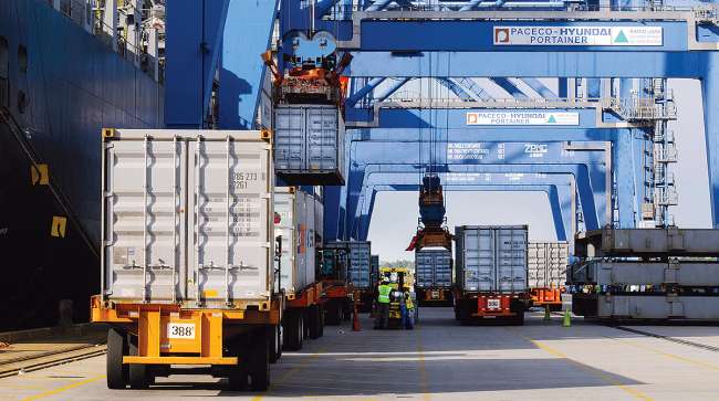 Trucks arrive with containers to be loaded onto a ship at the Port of Charleston