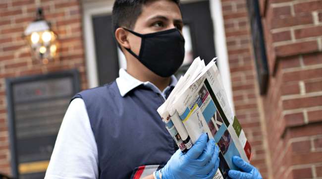 A USPS letter carrier is seen wearing a protective mask.