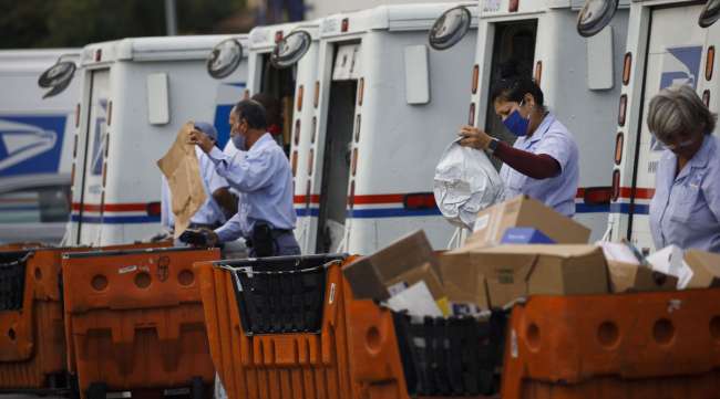 USPS employees load mail into delivery vehicles in Torrance, Calif., on Aug. 17.