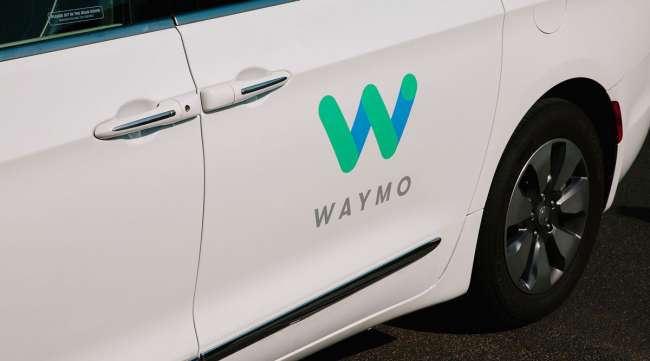 Waymo signage is displayed on the door of a Chrysler Pacifica autonomous vehicle in Arizona.