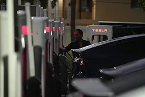 A driver charges his car at a Tesla Supercharger