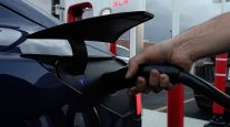  A motorist charges his electric vehicle at a Tesla Supercharger station