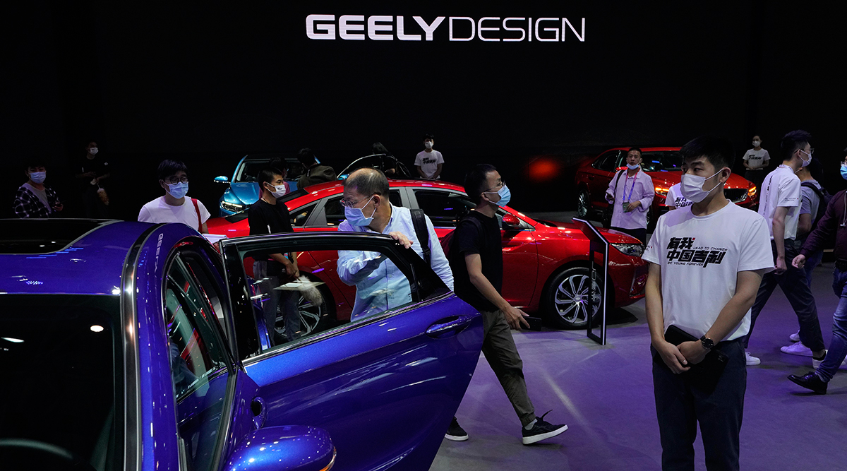 Visitors look at cars produced by Geely