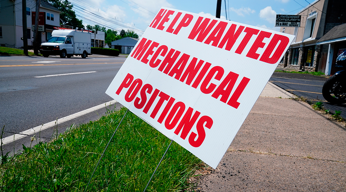 A help wanted sign is posted on the side of a road
