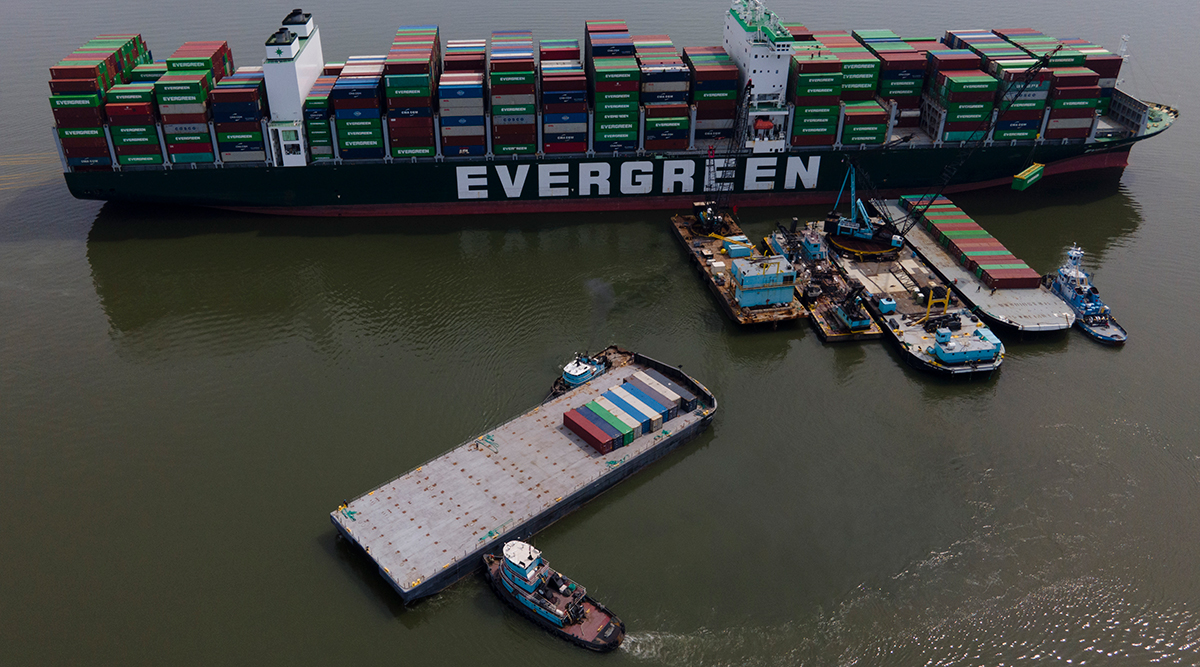 Tugboats align a barge near the container ship Ever Forward
