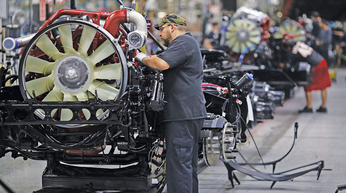 Workers installing engines at a Mack Trucks plant