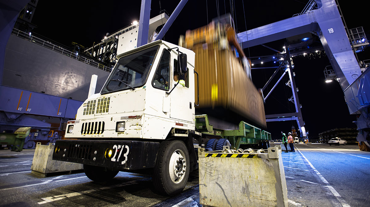 A container is loaded onto a flatbed truck at the Port of Long Beach