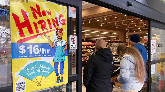 A hiring sign is displayed at a grocery store