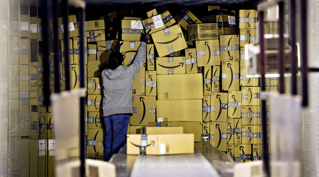 A worker unloads a truck of Amazon packages at a UPS hub in Hodgkins, Ill.