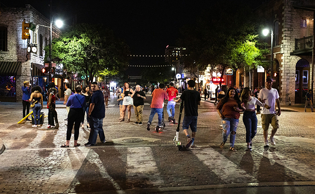 People gather on Sixth Street at night in downtown Austin