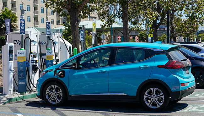 Electric vehicles can be seen charging at a shopping center in Emeryville, Calif.