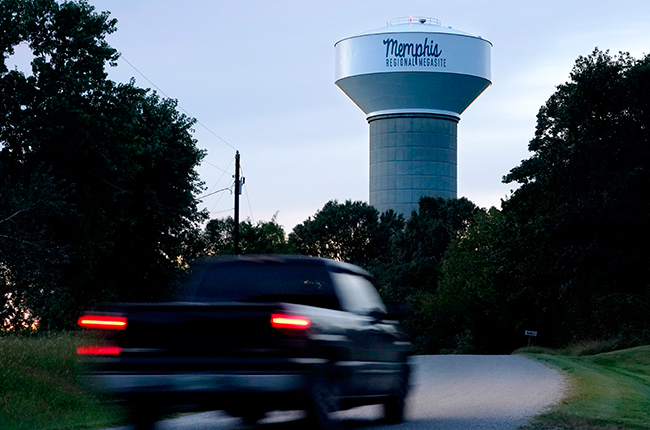 A truck drives down a rural road near a water tower marking the location of Ford's Memphis Regional Supersite
