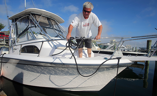 Rob Edwards, from Newport, R.I., adds extra lines to secure his boat at the Goat Island Marina