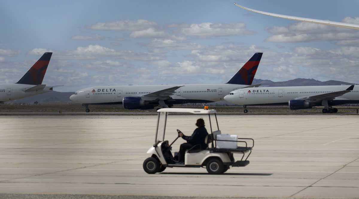 A ground staffer drives a cart past Delta Air Lines aircraft parked at a field in Victorville, Calif., on March 23.