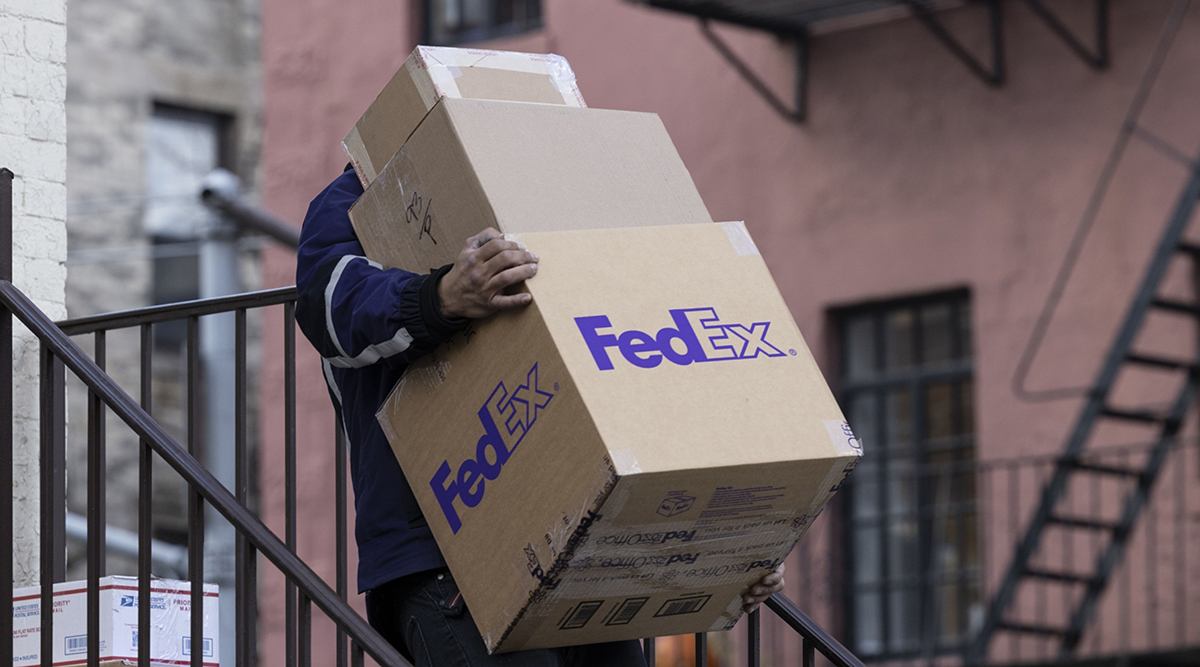 A FedEx courier carries packages