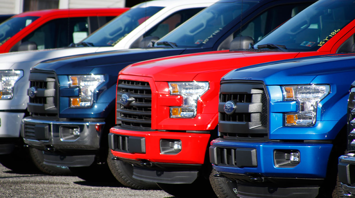 Row of Ford F-150 pickup trucks at a dealer lot