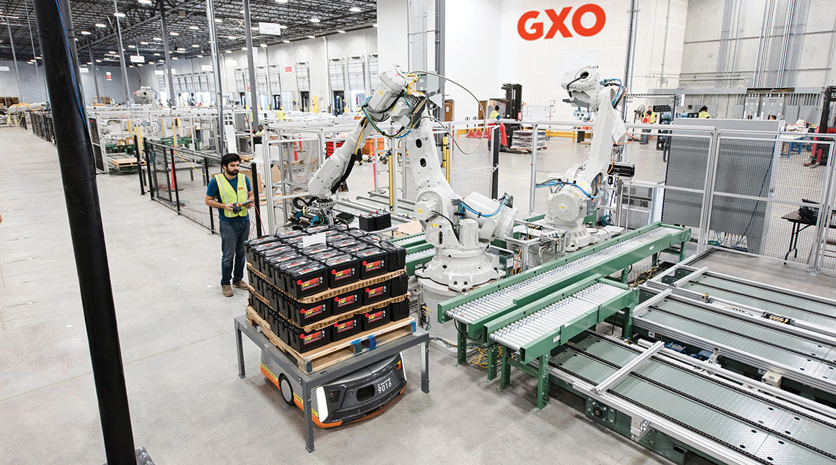 A GXO employee operates a robotic arm. 