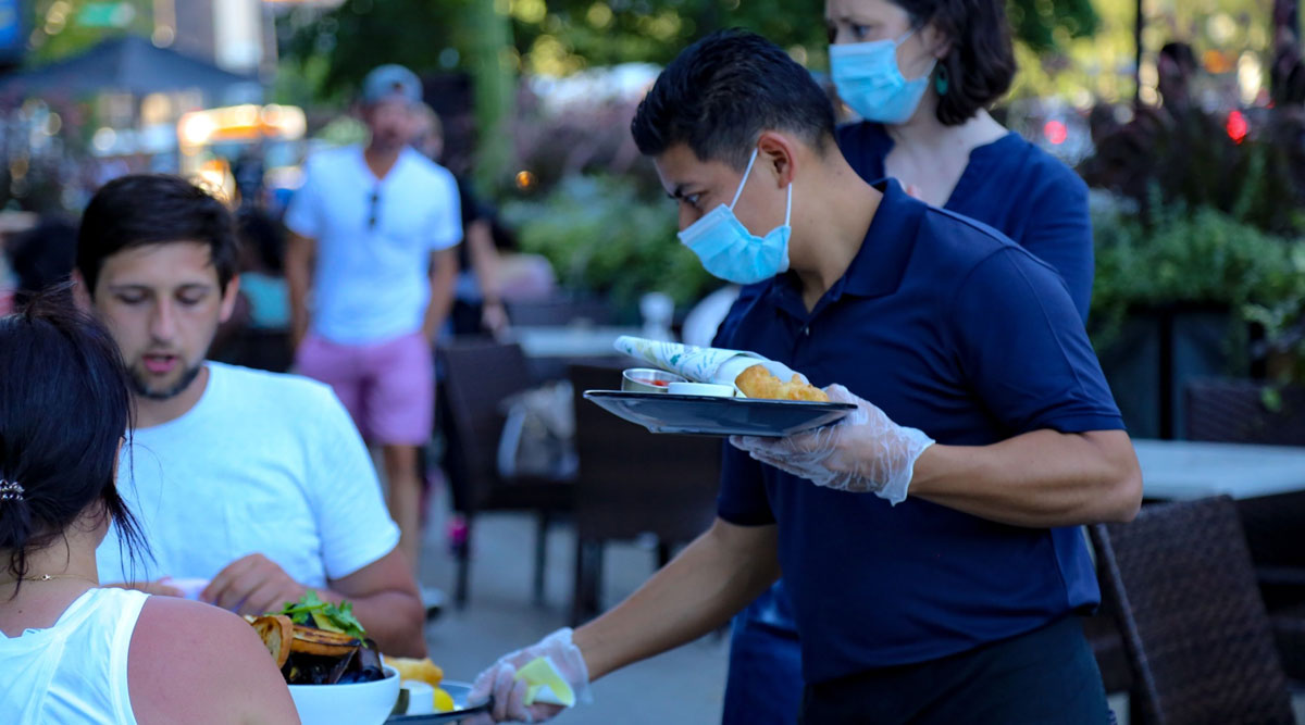 A waiter wearing protective equipment serves food.