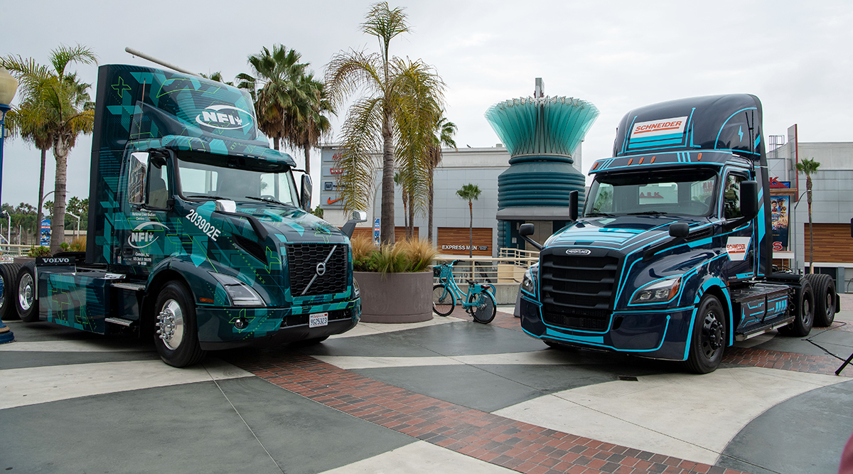 Volvo and Freightliner battery-electric trucks displaying NFI and Schneider branding