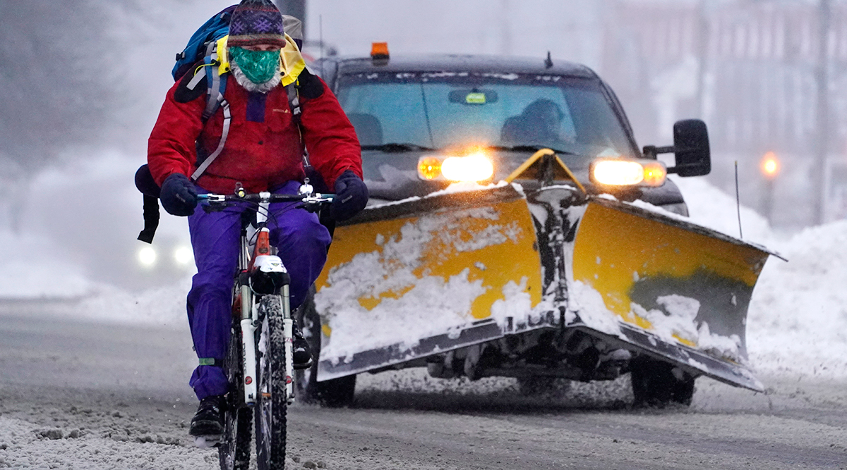 A bicyclist peddles on slick roads during a winter snowstorm in Brunswick, Maine. (Robert Bukaty/Associated Press)