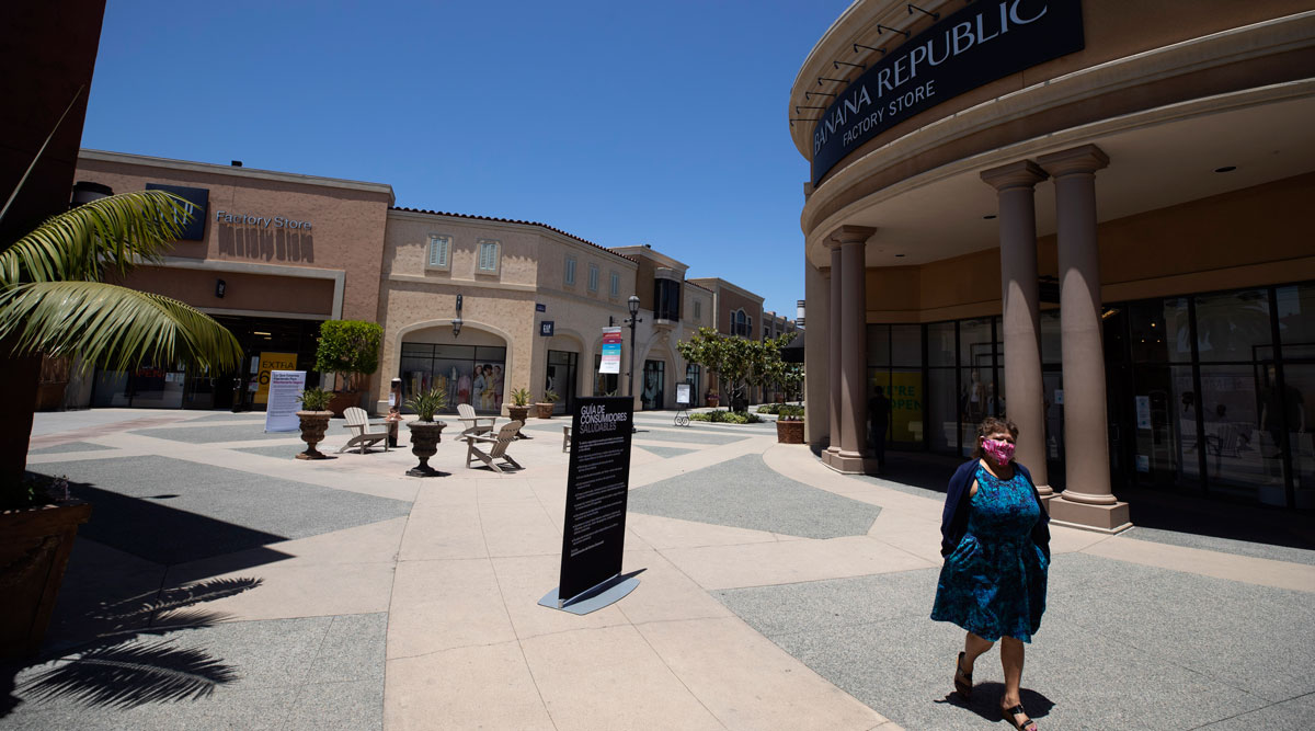 A woman wearing a mask walks through a San Diego outlet mall on May 26.