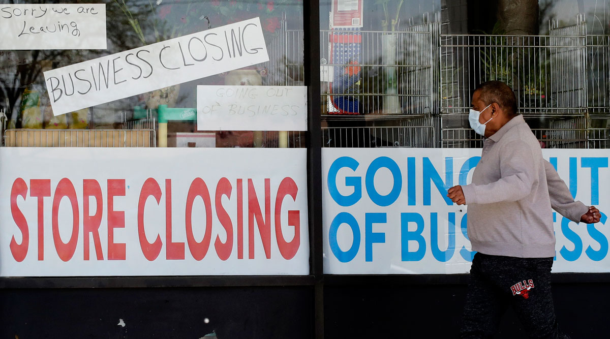 A man looks at signs of a closed store due to COVID-19 in Niles, Ill., on May 21.