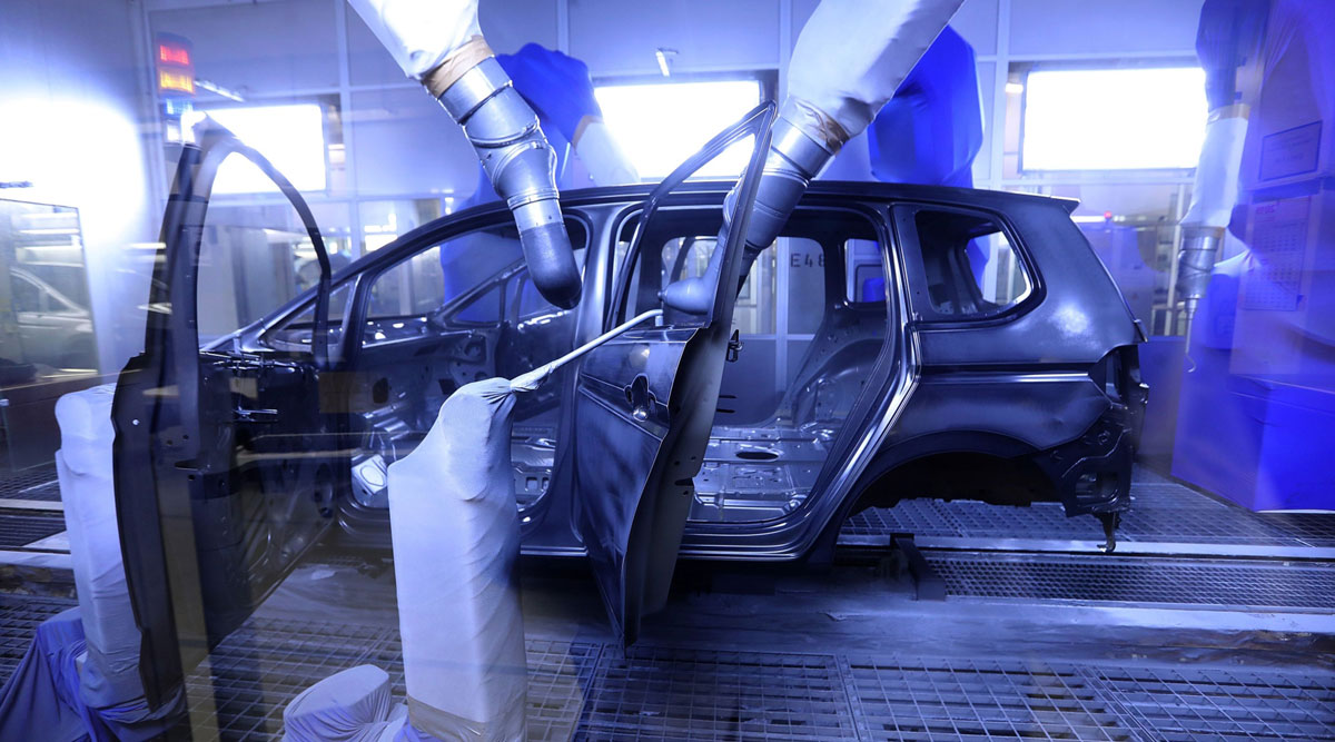 Robotic arms spray a Volkswagen vehicle in paint shop of company's Wolfsburg, Germany, factory.