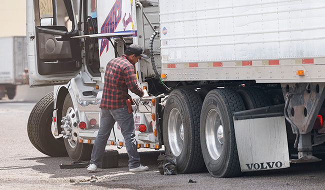 A truck driver performs required repairs after being inspected by Texas state troopers