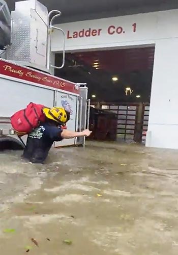 A Naples, Fla., firefighter carries gear in high water near his flooded fire station