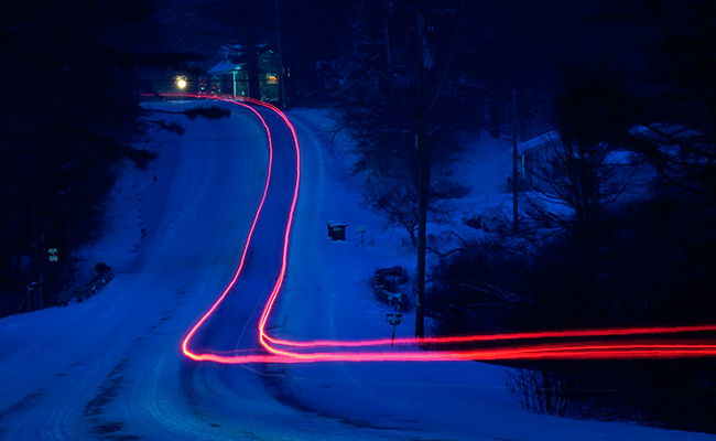In a photo taken with a long exposure, a car leaves a trail of light during a snowstorm in Freeport, Maine. 