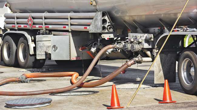 Tanker deposits fuel into a storage tank at a service station