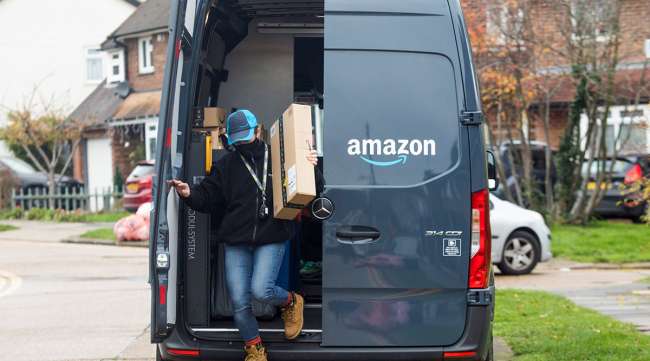 An Amazon.com Inc. delivery driver takes an order from a delivery van