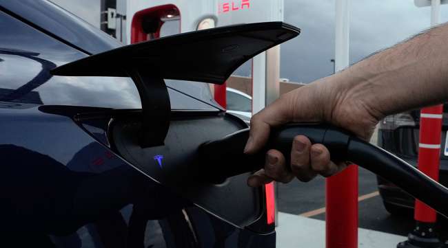 A motorist charges his electric vehicle at a Tesla Supercharger station