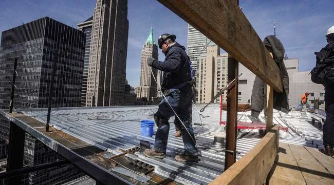 Construction workers install roofing on a high rise in Manhattan
