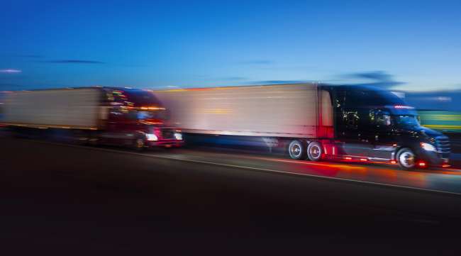 Blurred trucks on highway at dusk