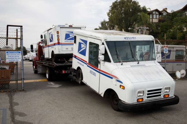 USPS mail trucks arrive on a tow truck to a post office in California in August 2020. (Patrick T. Fallon/Bloomberg News)