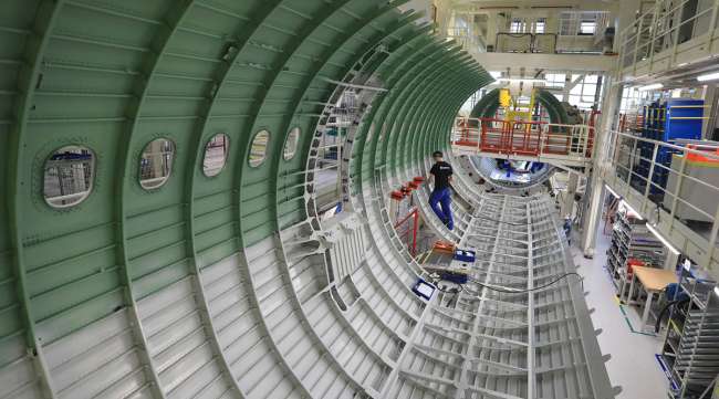 An employee works on an Airbus SE A320 aircraft at an assembly line hangar in Hamburg, Germany, in 2019.