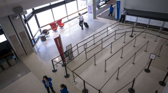 A pilot pulls luggage while walking past an empty security area at San Francisco International Airport on April 2.