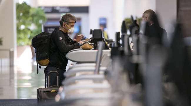 A traveler wearing a protective mask and gloves checks in at the Delta Air Lines counter at San Francisco International Airport on April 2.