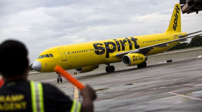 An aircraft marshal guides a Spirit Airlines plane on the tarmac at Fort Lauderdale International Airport.