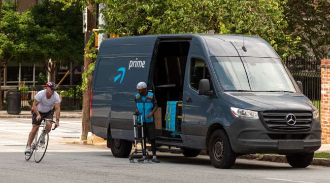 A pedestrian rides a bike past an Amazon Prime delivery van in Atlanta on July 21.