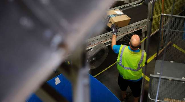 An employee collects a package from a conveyor at the Amazon fulfillment center in Robbinsville, N.J., in 2018.